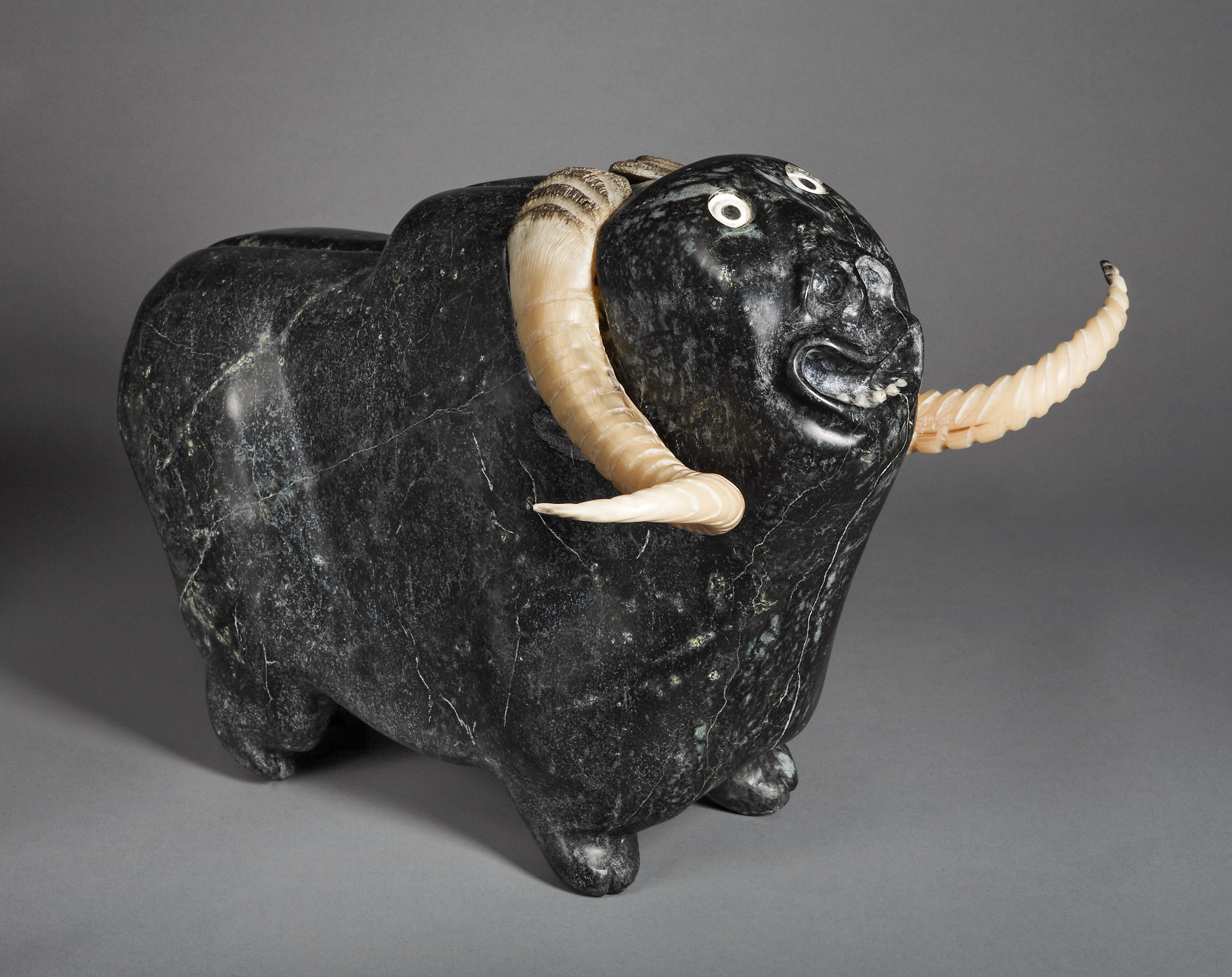 Judas Ullulaq, Boeuf musqué au visage humain, 1994. Pyroxénite, corne de boeuf, bois de caribou et albâtre, 41,4 x 49,3 x 54,7 cm. MNBAQ, Collection d'art inuit Brousseau, achat grâce à une contribution spéciale d'Hydro-Québec (2005.2473). Droits réservés Canadian Arctic Producers. Photo : MNBAQ, Isabel Trépanier